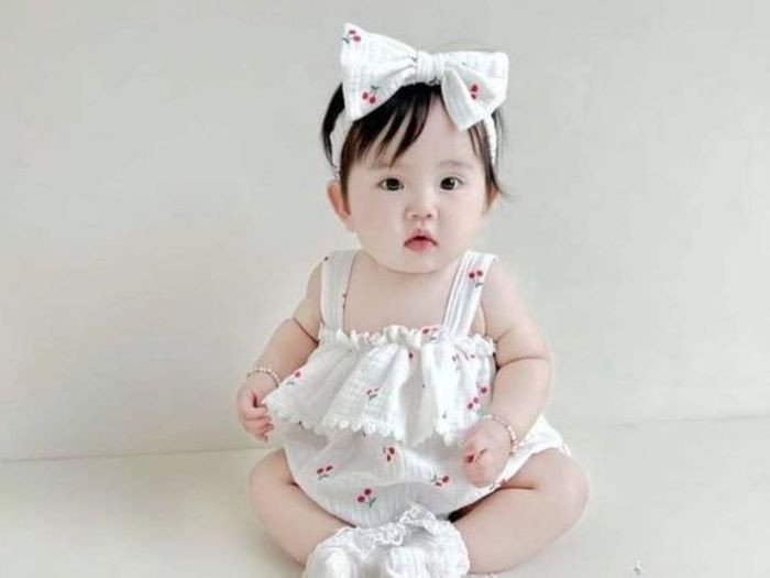 Bé gái đội vòng hoa cúc, ngồi giữa đồng hoa, thể hiện sự gần gũi với thiên nhiên