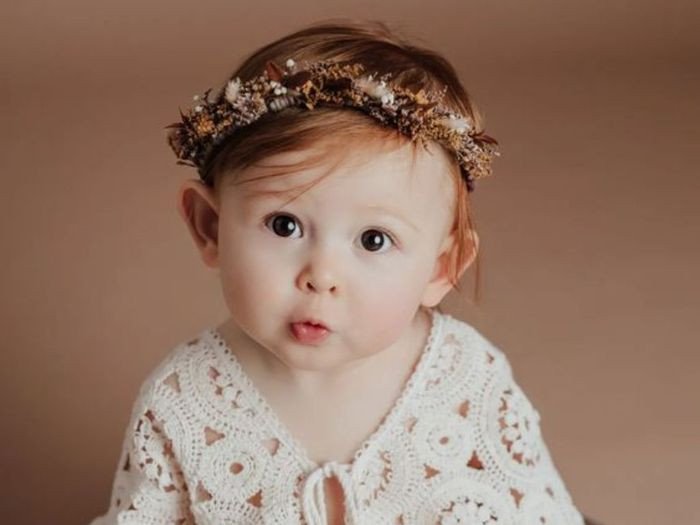 Bé gái ngồi trên ghế với trang phục sang trọng, toát lên vẻ cao quý