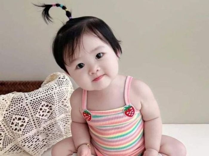 Bé gái với nụ cười rạng rỡ và mái tóc bồng bềnh, tượng trưng cho vẻ đẹp đáng yêu