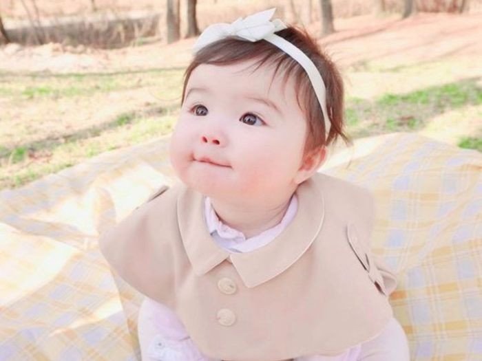 Bé gái với vòng hoa trên đầu, nụ cười tươi thể hiện sự hạnh phúc và may mắn