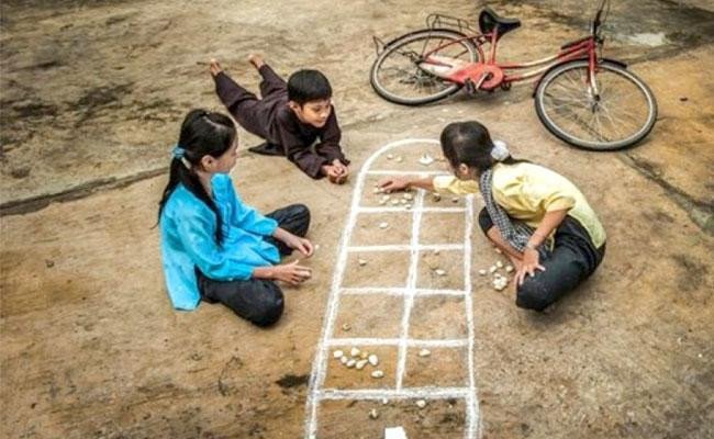 Hình ảnh minh họa trò chơi ô ăn quan với hai người chơi trên chiếu cói.