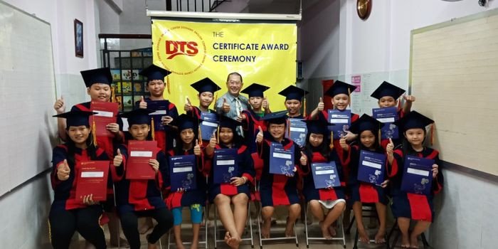 Học sinh ngồi trong một không gian học tập hiện đại, nhìn lên bảng với tinh thần học hỏi, thể hiện sự tương tác trong môi trường học tiếng Anh