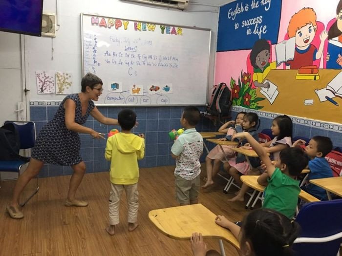 Học sinh ngồi trong một phòng học sáng sủa, đang viết bài, thể hiện môi trường học tiếng Anh tích cực