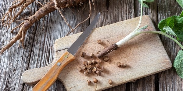 Một người đàn ông đang cắt nhỏ rau củ trên thớt với dao bếp.