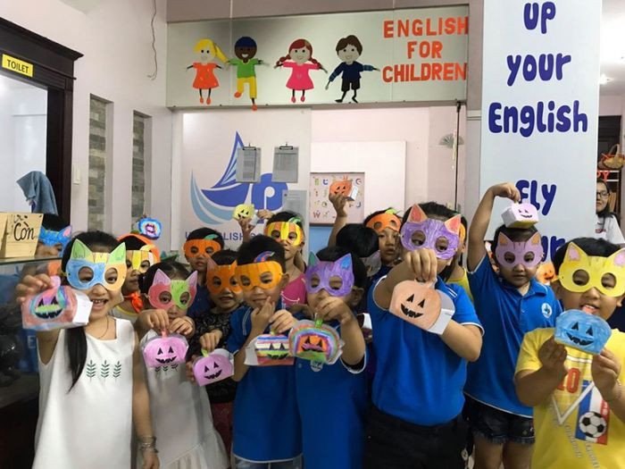 Một nhóm học sinh nhỏ tuổi đang ngồi học trong lớp cùng một giáo viên, minh họa việc học tiếng Anh cho trẻ em