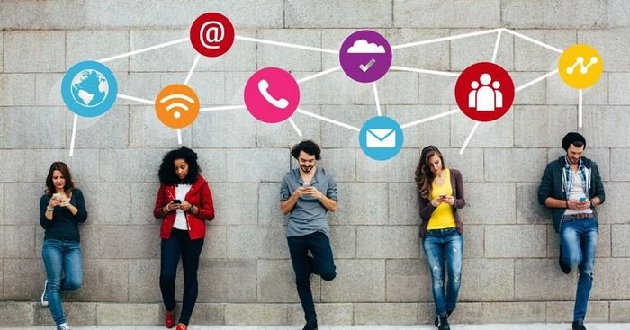 Người dùng máy tính với biểu tượng mạng xã hội, thể hiện tác động của truyền thông kỹ thuật số và từ vựng tiếng Anh liên quan.