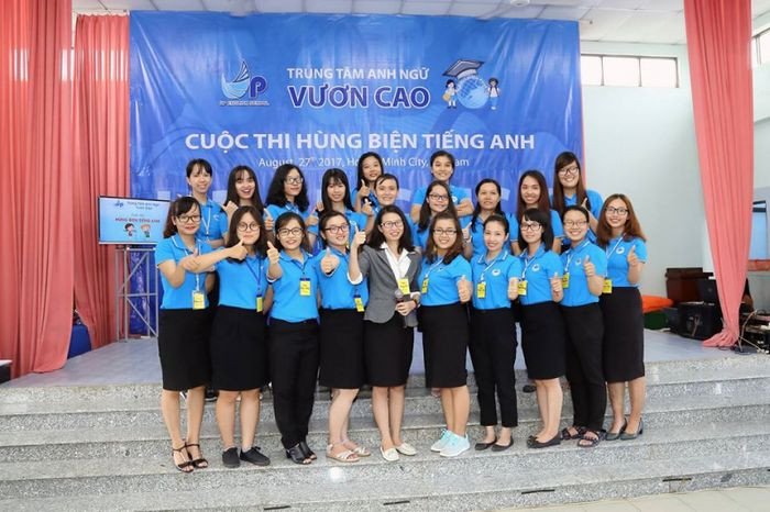 Nhiều học sinh đang ngồi trong lớp học, có vẻ là đang tham gia một hoạt động nhóm, cho thấy môi trường học tiếng Anh năng động